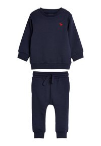 Navyblaues Baumwoll-Sweatshirt und Jogginganzug-Set. Das Sweatshirt hat ein rotes gesticktes Detail; die Jogginghose verfügt über einen verstellbaren Bund und Rippbündchen.