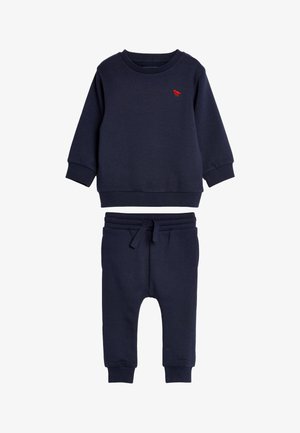 Granatowy bawełniany zestaw bluz i dresów. Bluzka ma czerwony haft; spodnie dresowe mają regulowany pas i ściągacze przy nogawkach.