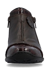Bottine en cuir marron avec bout et bordure brun foncé brillant, fermeture éclair sur le côté et fleur décorative sur la partie supérieure extérieure.