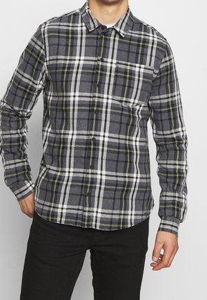 Camisa de cuadros en gris, blanco y verde, con un diseño abotonado, mangas largas y un bolsillo en el pecho. El material parece suave y texturizado.