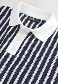 Blau-weiß gestreiftes Poloshirt mit weißem Kragen und drei Knöpfen. Der Stoff hat eine strukturierte Oberfläche.