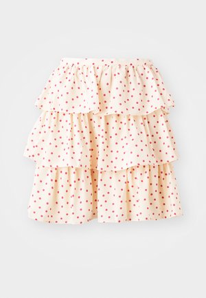 Kortsäär mõõduka kreemivärvi kangast, millel on punased täpid. Omab kolme kihti volange alläärtes ja elastset vööd.