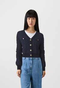 Námořnická modrá pletená cardigan s kabelkovým vzorem, V-výstřih, dlouhé rukávy, šest dekoračních knoflíků a přiléhavý pas.