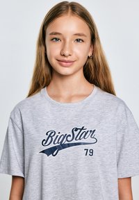 Hall ainult hall puuvillane t-särk, millel on tumesinine "BigStar" logo ja number "79". Särgil on ümar kaelus ja lühikesed varrukad.