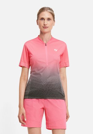 Woman wearing a short-sleeve pink and gray gradient cycling jersey with half zipper and matching pink shorts, standing against white background.