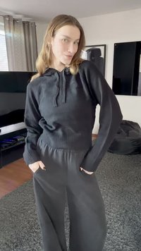 Black knit hoodie with a ribbed hem and front pocket paired with black wide-leg pants, creating a cohesive monochromatic ensemble.