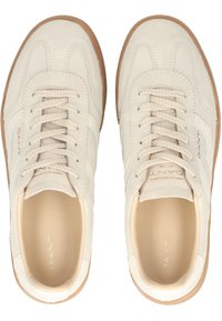 Zapatos deportivos de ante beige con cuero texturizado, cordones planos y suela de goma marrón clara. Nombre de la marca grabado y detalle de rayas sutil.