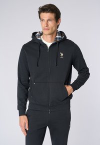 Felpa nera con zip, foderata in plaid, con logo ricamato, cappuccio con lacci e tasche frontali. Tessuto liscio, vestibilità rilassata.