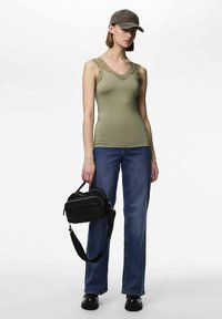 Oliiviroheline topp pitsist ääristusega, kombineeritud tumeliste sirge säärega teksade ja mustade platvormkingadega. Must ristkorpus-kott kahe tõmblukuga taskuga.