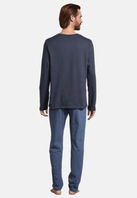 Maglietta a maniche lunghe navy, vestibilità rilassata, tessuto morbido; abbinata a pantaloni azzurri chiari, a taglio dritto, con cintura elastica e texture liscia.