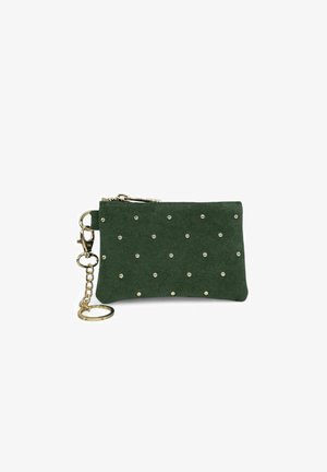 Pochette en suède verte avec une fermeture éclair dorée et une chaîne, décorée de petits clous dorés disposés en motif sur le devant. Design compact.