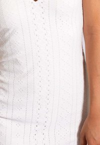 Weißes ärmelloses Kleid mit V-Ausschnitt, das mit strukturierten Lochmustern und vertikalen Streifen versehen ist. Weicher Stoff mit atmungsaktivem Design.