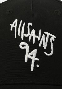 Cappellino nero con testo ricamato bianco che recita "ALLSAINTS 94". Il tessuto è liscio, con un design strutturato e una visiera curvata.