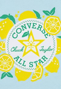 Ανοιχτό μπλε μπλουζάκι με στρογγυλή εικόνα που απεικονίζει κίτρινα λεμόνια και ένα πράσινο αστέρι, με την ένδειξη "CONVERSE Chuck Taylor ALL STAR".