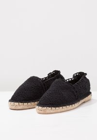 Espadrillas in cotone nero con punta affusolata, suole in stile juta e tacco basso. Presentano un design a trama aperta lungo i bordi.
