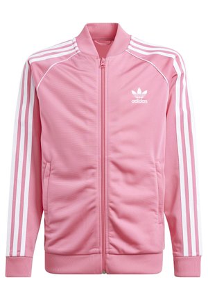 Różowa kurtka sportowa Adidas z białymi trzema paskami na rękawach, zamkiem błyskawicznym z przodu, prążkowanym kołnierzem, mankietami, dolnym ściągaczem i logo Adidas na piersi.