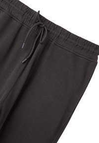 Černé tepláky s elastickým pasem a stahovací šňůrkou, vyrobené z měkké, pletené látky vhodné pro každodenní nošení.