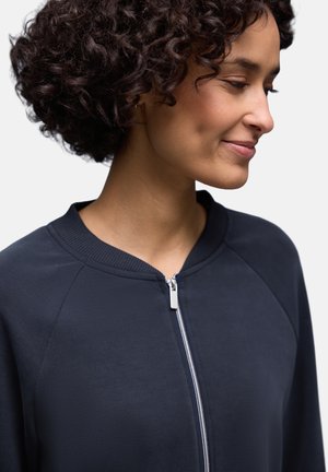 Marineblaue Jacke mit Reißverschluss, geripptem Kragen und Raglanärmeln. Glatter Stoff, ausgestattet mit einem silbernen Reißverschluss und minimalistischem Design.