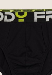 Braguita negra de algodón con una cinturilla ancha elástica con marcas en amarillo y blanco. Textura suave con un diseño ajustado.