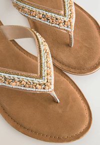 Hnědé sandály s tkanými beaded popruhy včetně světle modrých a béžových akcentů. Měkká semišová stélka a tenký kovový pásek.