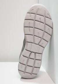 Gray athletic shoe sole with a textured pattern, featuring deep grooves for traction and flexibility. Slightly raised edges around the heel.