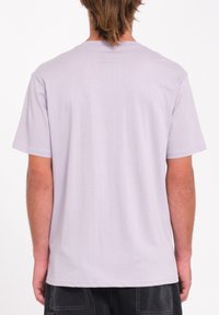 T-shirt lilas à manches courtes avec col rond, fabriqué en coton doux, doté d'un design uni et d'une coupe décontractée. Aucunes graphiques visibles.