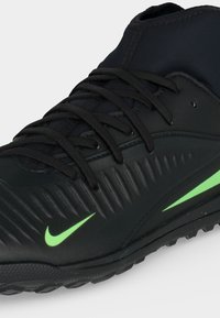 Μαύρο αθλητικό παπούτσι Nike με σήμα Swoosh σε λαχανί πράσινο χρώμα, υφασμάτινες πλευρικές λεπτομέρειες, μαύρα κορδόνια και στιβαρή σόλα σχεδιασμένη για πρόσφυση.