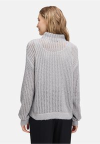 Grauer Strickpullover mit lockerer Passform, hoher Kragen, offenes Strickmuster und gerippte Bündchen. Weicher Stoff und lässiges Design.