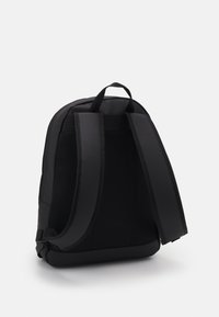 Zaino nero realizzato in tessuto resistente con rete, dotato di spallacci imbottiti regolabili, maniglia superiore e un design snello.