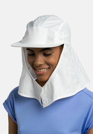 Persona que lleva una gorra protectora blanca contra el sol con solapa para el cuello y orificios de ventilación, combinada con una camisa azul de manga corta, sonriendo hacia abajo.
