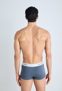 Men's boxer briefs in gray fabric with a white waistband featuring the Calvin Klein logo. The design is fitted, emphasizing athletic form.