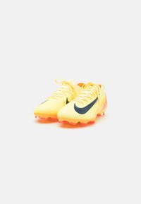 Futbalové kopačky Nike v jasne žltej farbe s čiernym swooshom. Textúrovaný sieťový vrch a živé ružové akcenty na podrážke. Šnurovací dizajn.