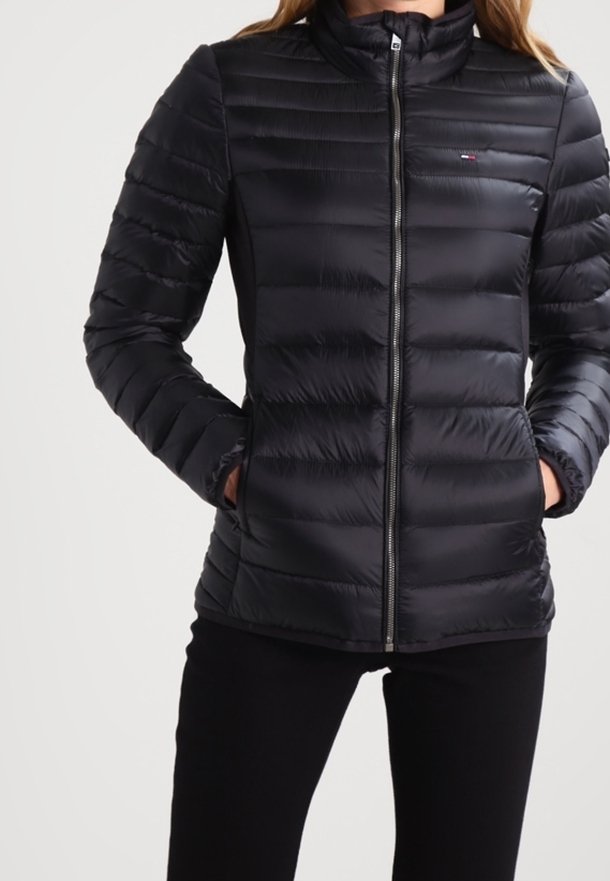 Svart puffjacka med blixtlås fram, hög krage, horisontellt quiltad design och sidofickor. Tillverkad av lätt, slätt material.