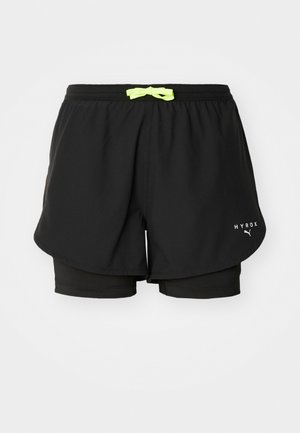 Shorts sportivi neri con un design a più strati, cordino verde neon, pantaloni interni attillati e logo stampato bianco.