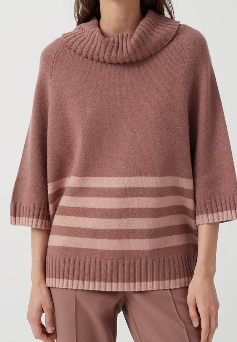 Pehmeä, vaaleanpunainen neulottu neulepaita, jossa on ribbikuvioinen kappalemallinen kaulus ja vaaleammansävyiset vaakasuorat raidat sekä väljät, lyhyet hihat.