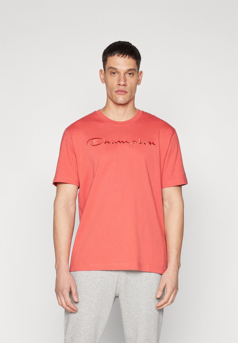 Rotes Baumwoll-T-Shirt mit kurzen Ärmeln und Rundhalsausschnitt, mit gesticktem "Champion"-Logo auf der Brust. Weiche, glatte Textur.