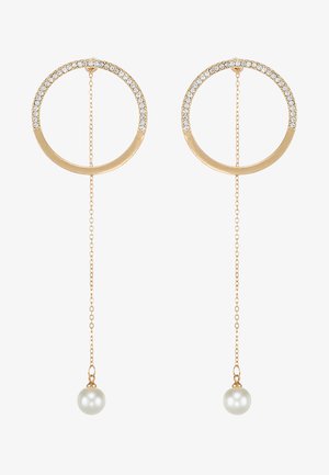 Boucles d'oreilles en or en forme de hoop avec des embellissements en cristal sur le dessus, agrémentées d'une chaîne se terminant par une perle ronde.