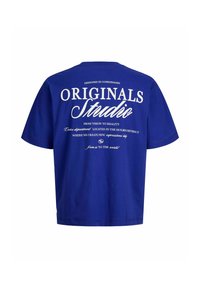 Μπλε κοντομάνικο t-shirt με λευκό κείμενο στην πλάτη που γράφει "Originals Studio" καθώς και επιπλέον μικρότερες σχεδιαστικές λεπτομέρειες και φράσεις.