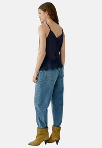 Navy camisole with lace bottom, paired with loose blue jeans and tan suede ankle boots featuring pointed heels. Silver hoop earrings.