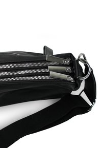 Zwarte leren tas met drie metalen ritsen, zilverkleurige hardware, een korte handgreep en een geweven stoffen schouderband.