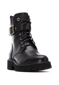 Botín negro de piel con hebilla de metal, cordones y detalles de brogue. Suela negra gruesa con relieve para mayor tracción. Textura suave en toda la superficie.