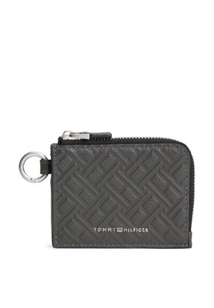 Cartera de cuero negro con cremallera, patrón geométrico en relieve y detalle de llavero metálico. Logotipo visible de Tommy Hilfiger en el frente.
