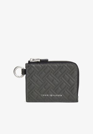 Czarny skórzany portfel zapinany na zamek błyskawiczny z tłoczonym geometrycznym wzorem i metalowym brelokiem do kluczy. Na przedniej stronie widoczne logo Tommy Hilfiger.