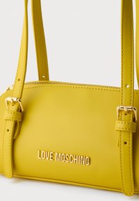 Κίτρινη τσάντα χειρός από τεχνητό δέρμα με εξαρτήματα σε χρυσαφί τόνο, ρυθμιζόμενα λουριά και ανάγλυφο λογότυπο "LOVE MOSCHINO" στο μπροστινό μέρος.