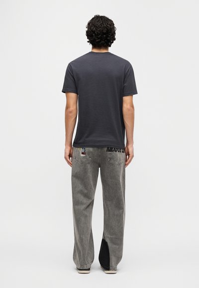 Γκρι κοντομάνικη μπλούζα με στρογγυλή λαιμόκοψη, σε συνδυασμό με γκρι τζιν παντελόνι με φαρδιά μπατζάκια, πλευρικές σχισμές και διακοσμητικές τσέπες.