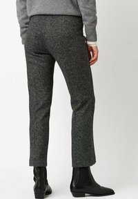 Szare spodnie z tweedu o prostych nogawkach, z delikatnymi czarno-białymi cętkami. Do tego czarne botki za kostkę.