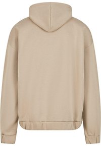 Beige hoodie med en blød tekstur, kengurulommer og lange ærmer. Har en hætte med snor og ribbede manchetter og kant.