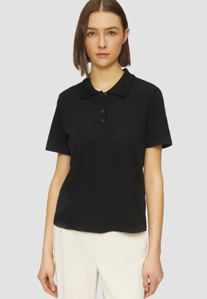 Polo noir, manches courtes, en coton doux, col classique, patte de boutonnage à cinq boutons, et coupe décontractée. Texture lisse, design minimal.
