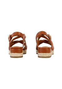 Sandales en cuir marron avec des brides croisées, un détail de boucle et une semelle intermédiaire en style espadrille tissée. Semelle plate avec un léger talon.