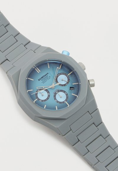 Γκρι πλαστικό ρολόι χειρός με μπλε καντράν χρονόμετρου, τρεις υποκαντράν, ένδειξη ημερομηνίας και λουράκι με συνδέσμους σε λευκό φόντο.